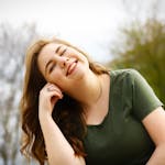 A carefree woman enjoying a sunny day outdoors, expressing pure happiness and relaxation.